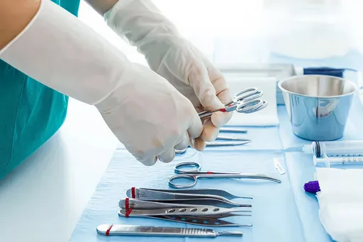 Gloved hands arranging surgical instruments on a sterile tray